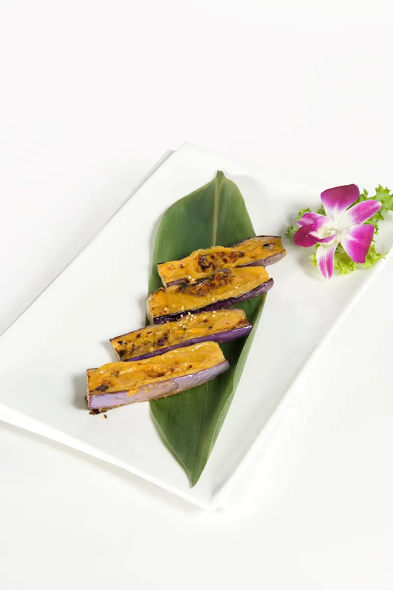 Miso glazed eggplant with sesame seeds served on a banana leaf at Asian Bistro
