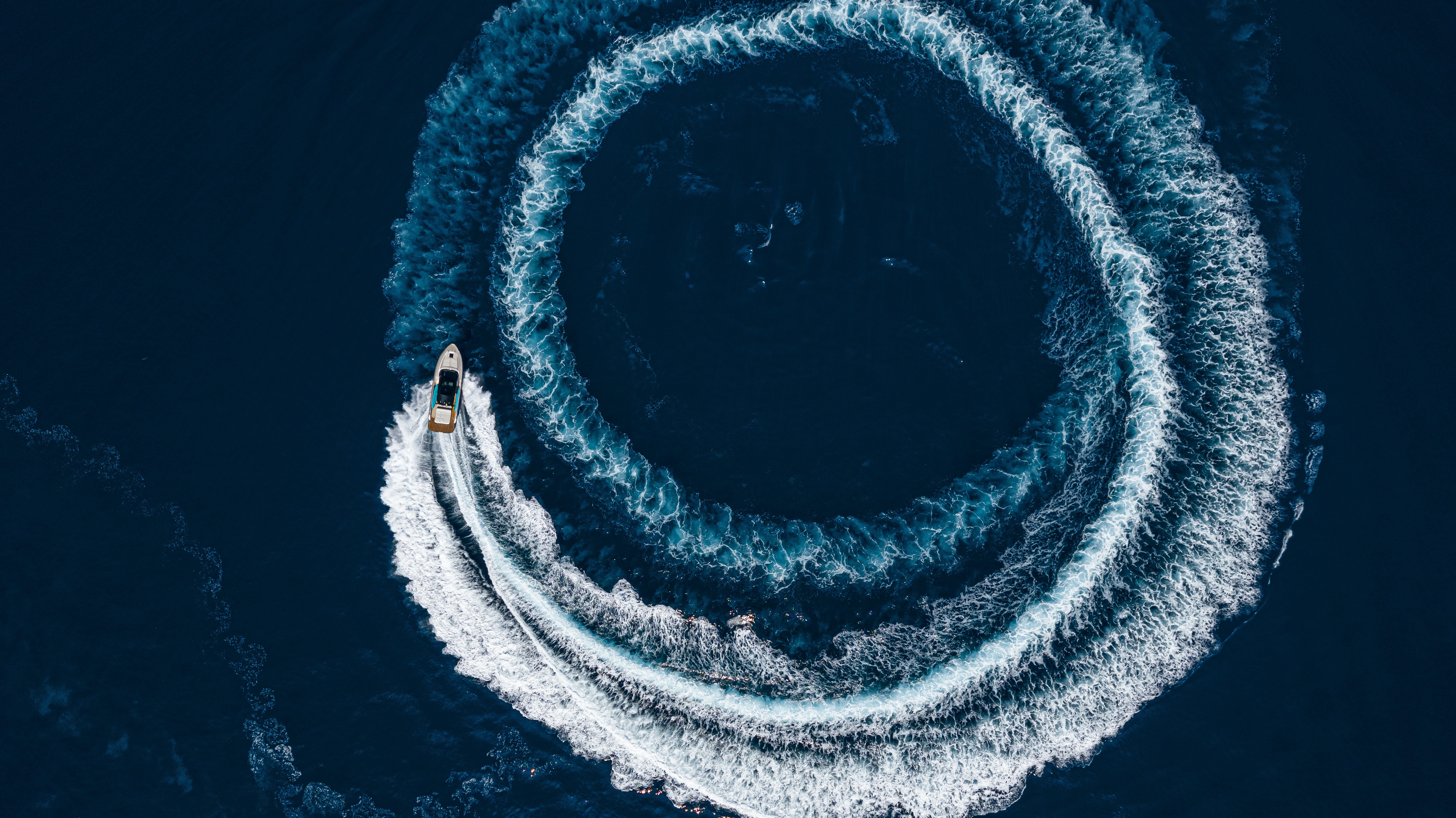 Aerial view of a boat creating circular wake in deep blue Italian waters