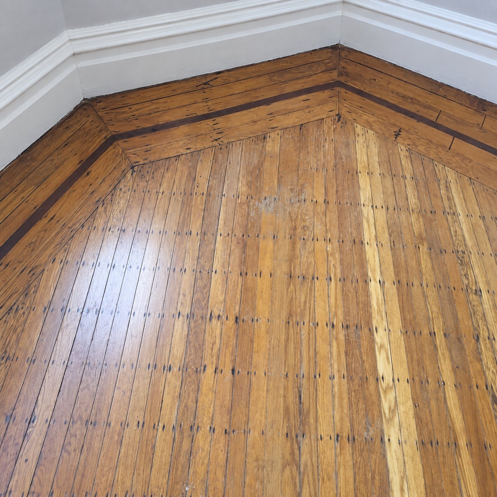 Worn hardwood floor with a dark border before restoration