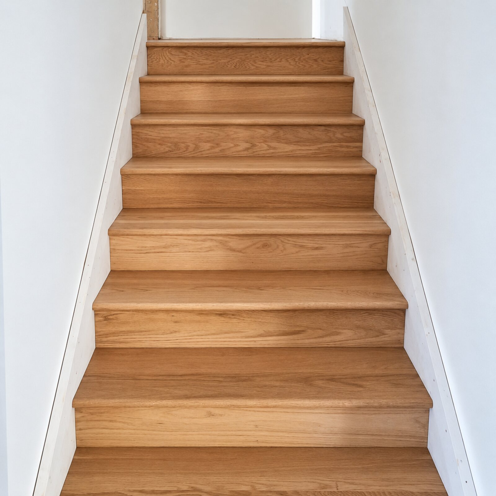 Natural oak staircase with matching oak flooring at its base