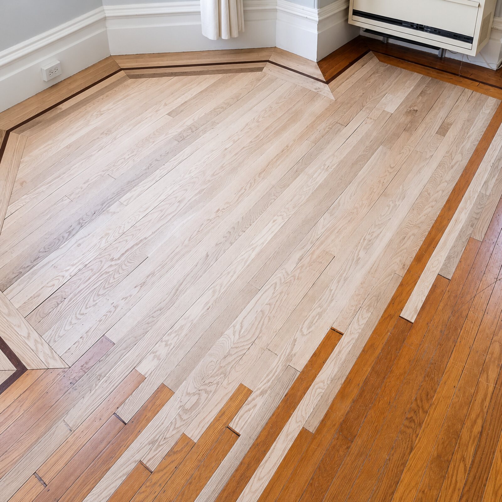 Oak flooring running past a kitchen island to a staircase with metal balusters