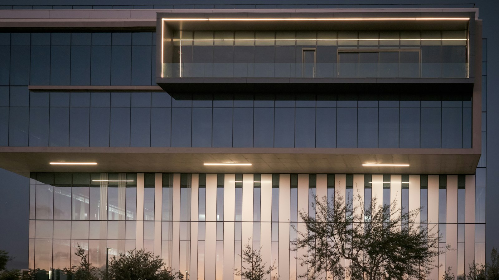 Modern commercial building exterior at dusk with its lights on