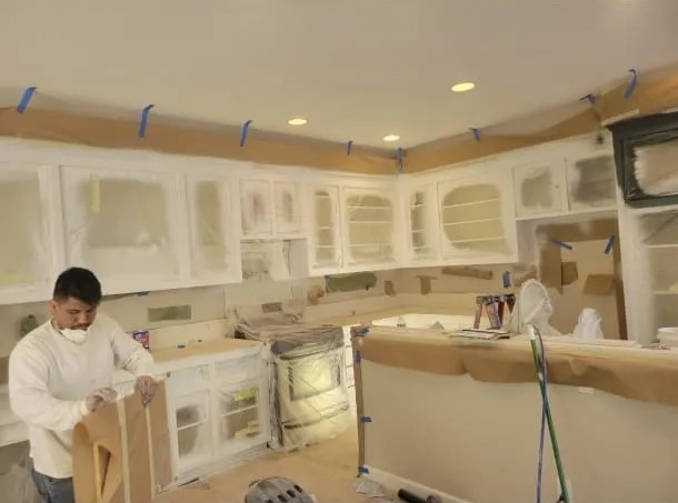 Gustavo Dominguez preparing kitchen cabinets with masking paper