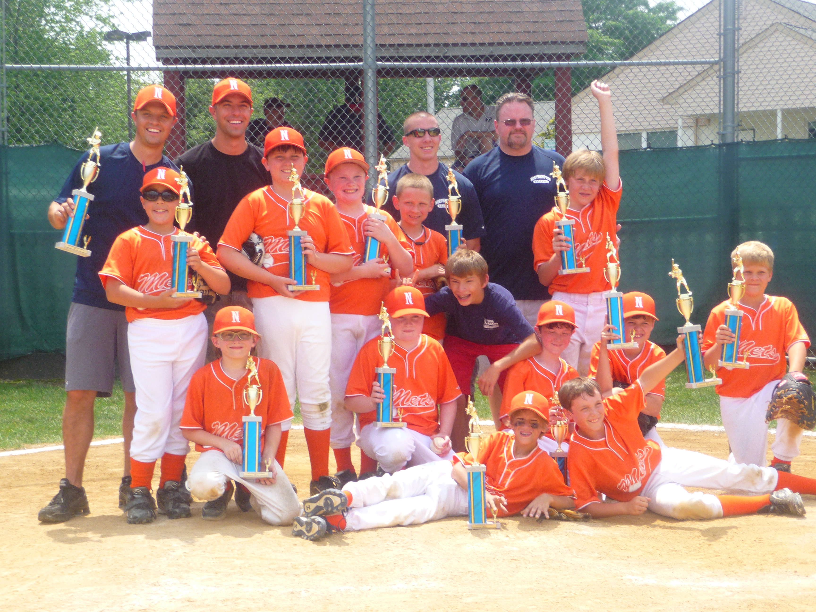 Michael Smedley and his Little League championship team celebrating with trophies on the field