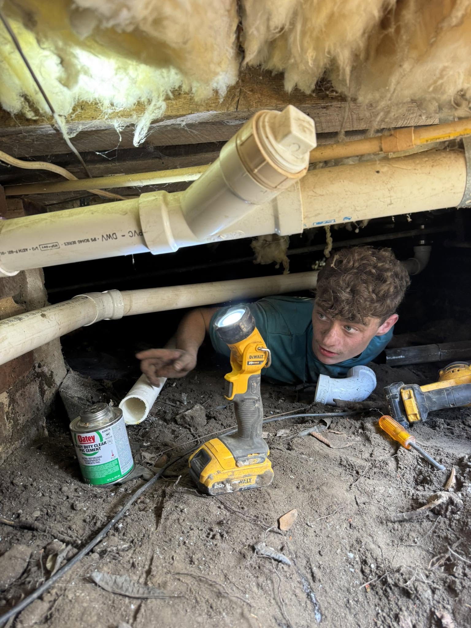 Drain Care LLC technician inspecting pipework under a Corinth-area home