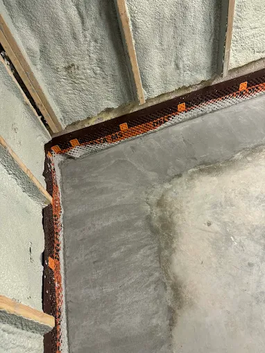 Interior perimeter drainage system with spray foam insulation and poured concrete floor