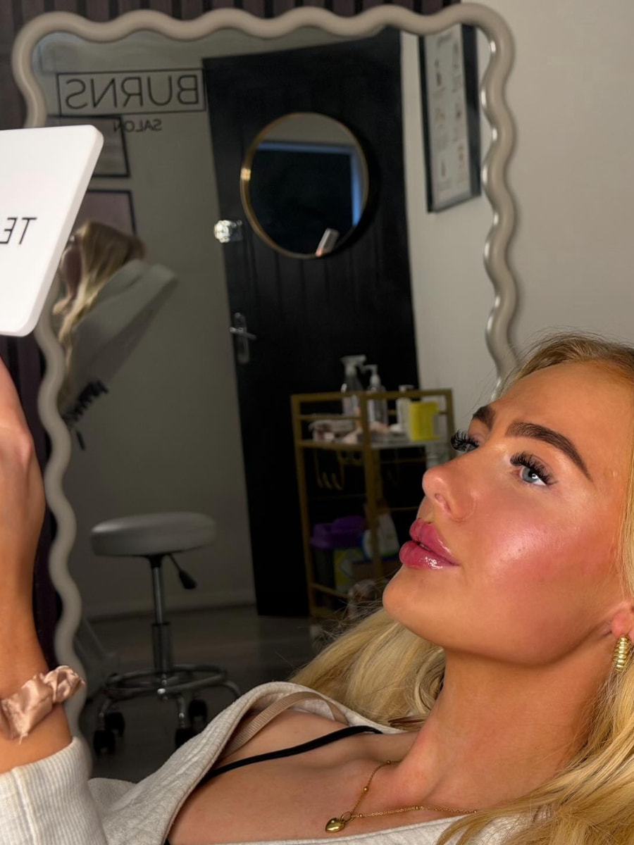 Client viewing fresh lip enhancement result in mirror at Burns Salon Luton
