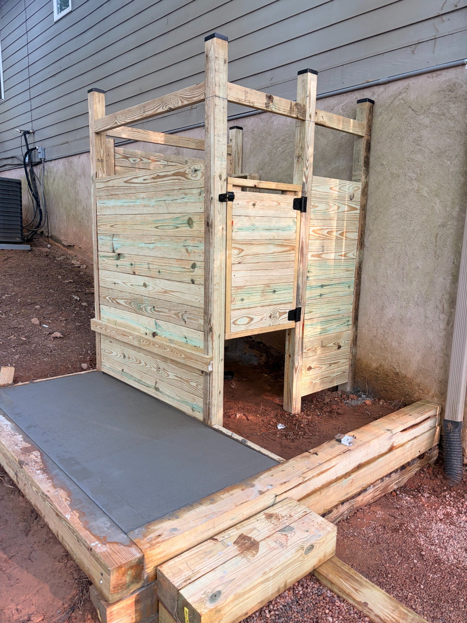 Wood privacy enclosure framing and concrete pad pour in progress by Limitless Construction Services