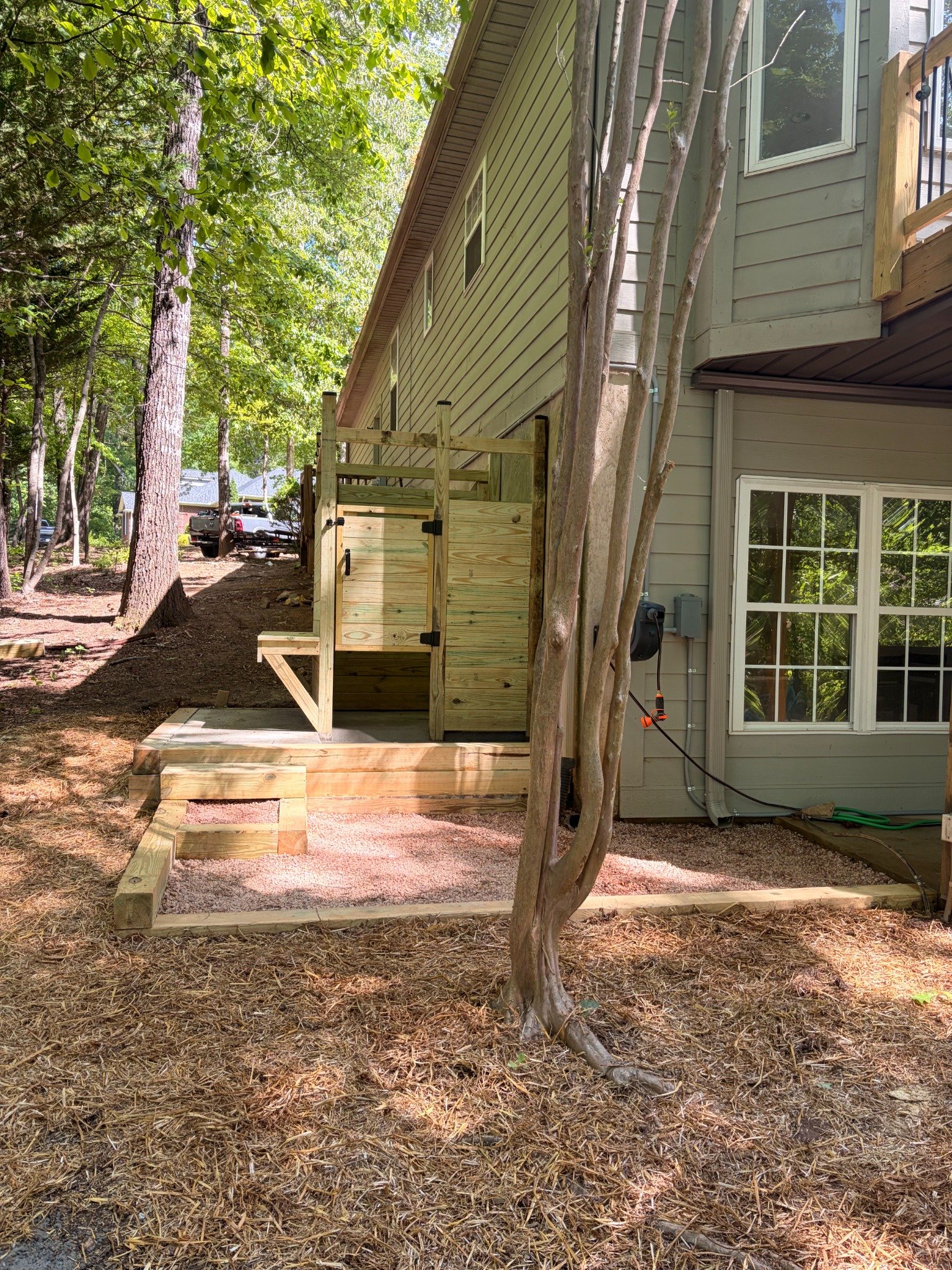 Side perspective of completed wood privacy enclosure and gravel landing by Limitless Construction Services