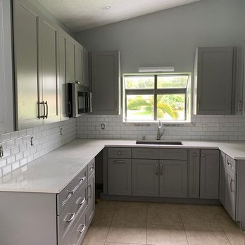 Remodeled kitchen with grey shaker cabinetry, white quartz countertops, and subway tile backsplash