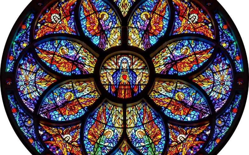 Intricate stained glass rose window depicting sacred geometric symmetry with angels and a central holy figure