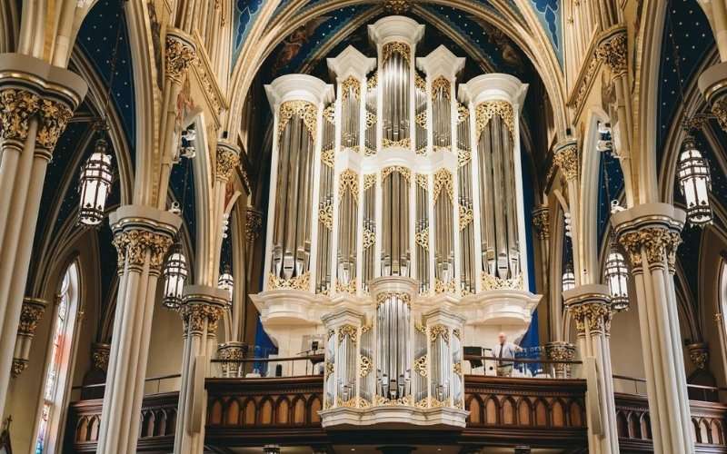 Monumental cathedral pipe organ with ornate white and gold gothic casework showing geometric proportion and sacred acoustic architecture