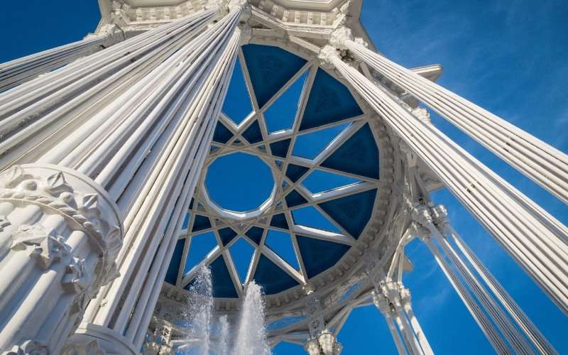 Intricate geometric star cupola and fluted columns of an open-air classical rotunda against a blue sky
