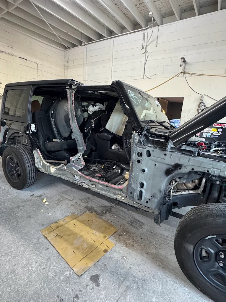 Black Jeep Wrangler undergoing structural frame overhaul in repair bay