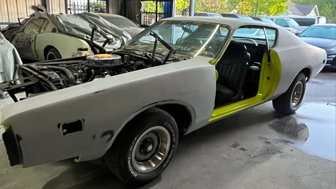 Vintage muscle car undergoing body restoration and priming in workshop