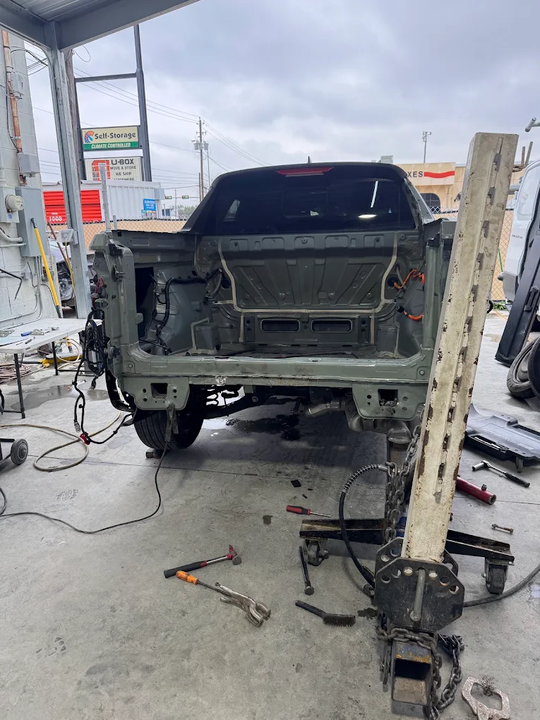 Rear truck frame structural disassembly and hydraulic alignment in shop bay