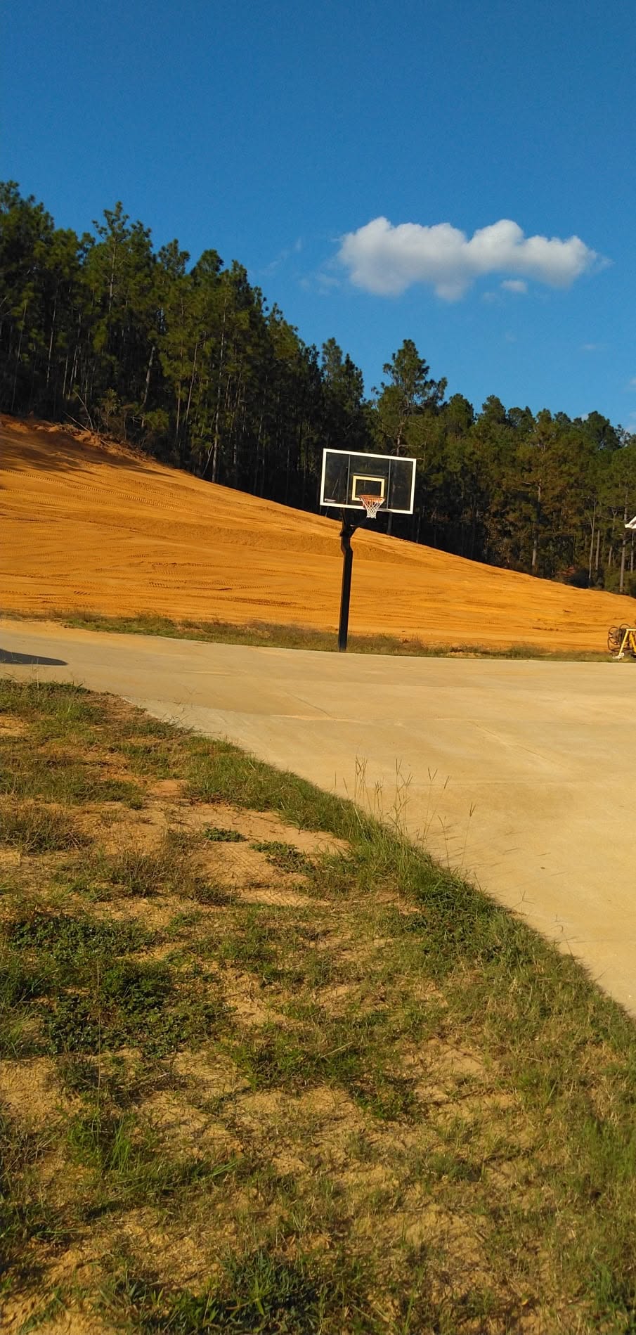 Breaking Ground sloped hill grading and contour earthwork bordering court and tree line
