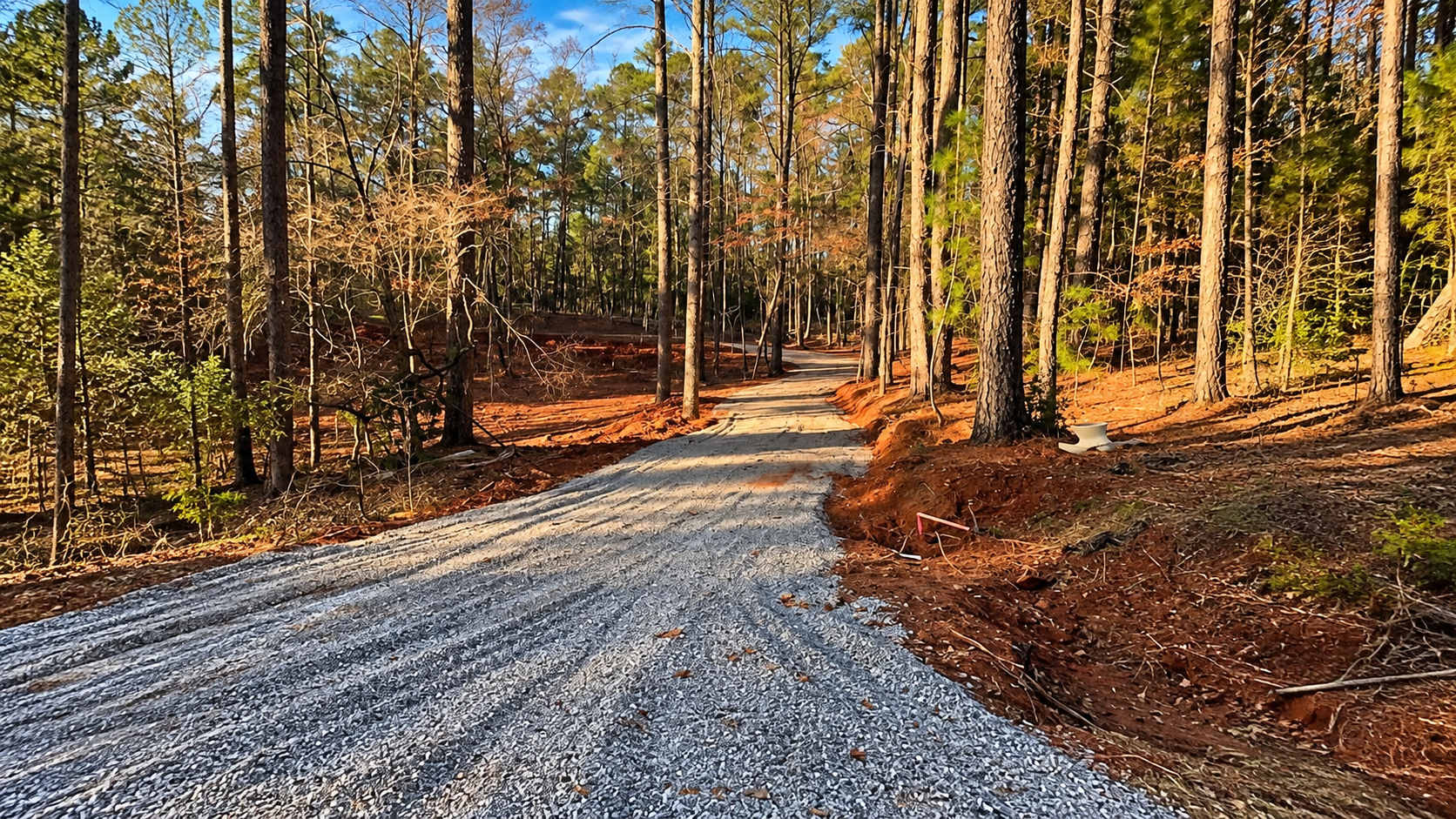 Finished crushed stone gravel driveway with graded shoulders through wooded acreage in Augusta, GA