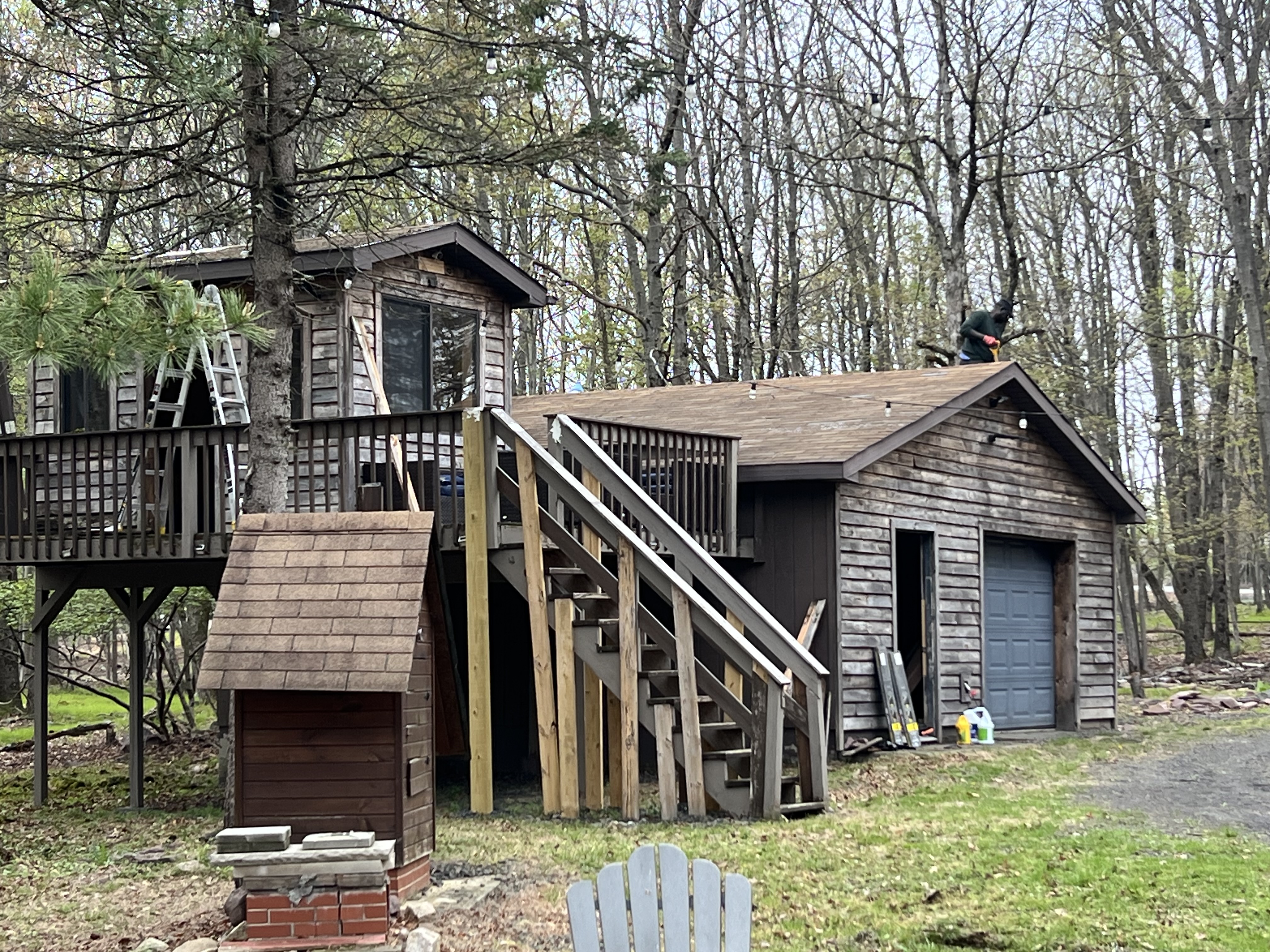 Poconos cabin before renovation — detached garage and stairway in need of repair and repainting