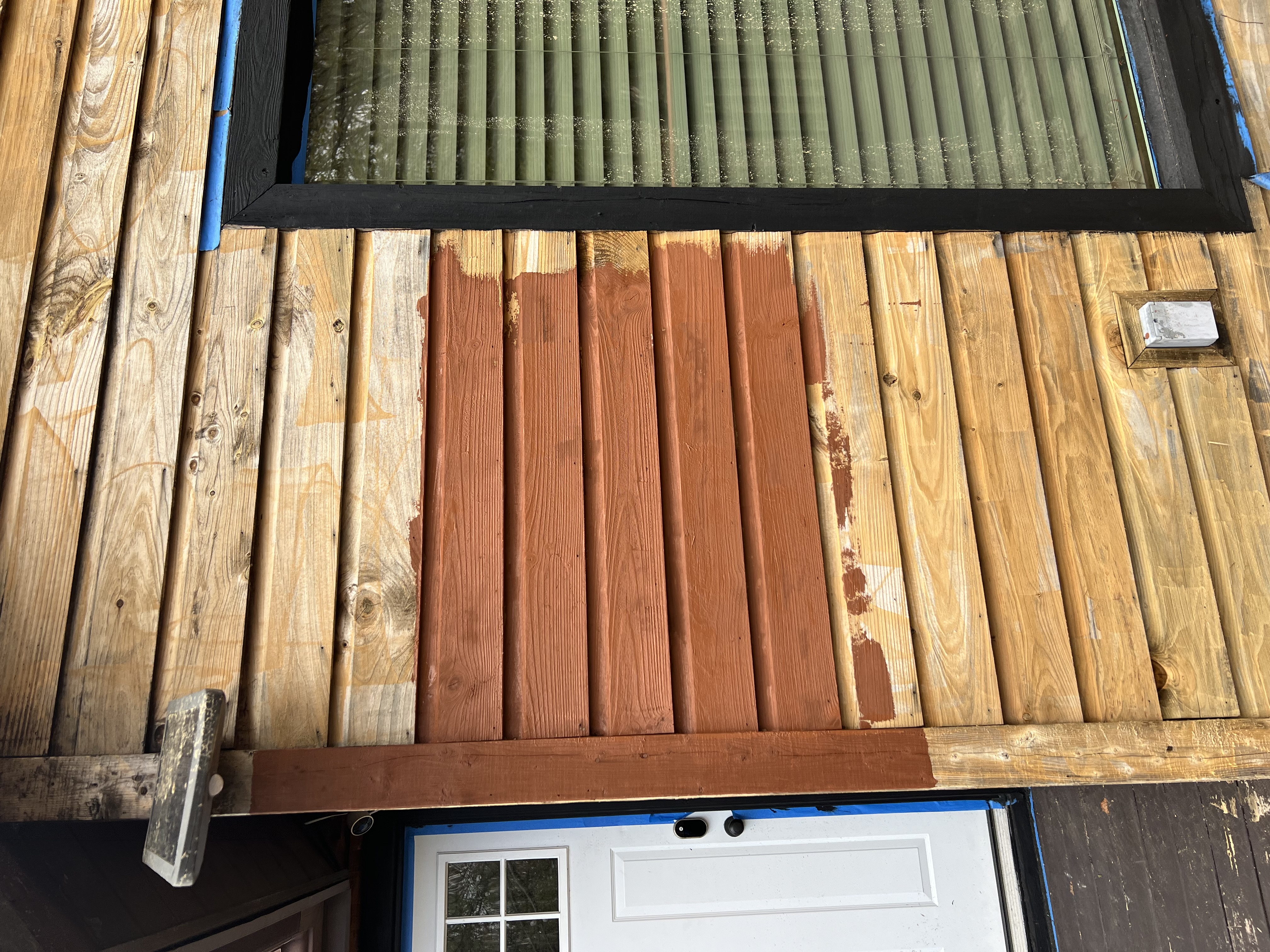 Poconos cabin in progress — close-up of fresh reddish-brown stain applied to weathered siding boards