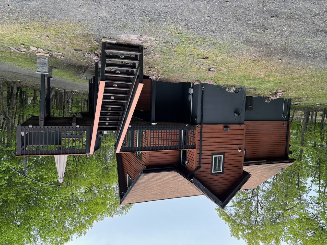 Poconos cabin after renovation — finished cabin profile with elevated deck staircase and outdoor umbrella
