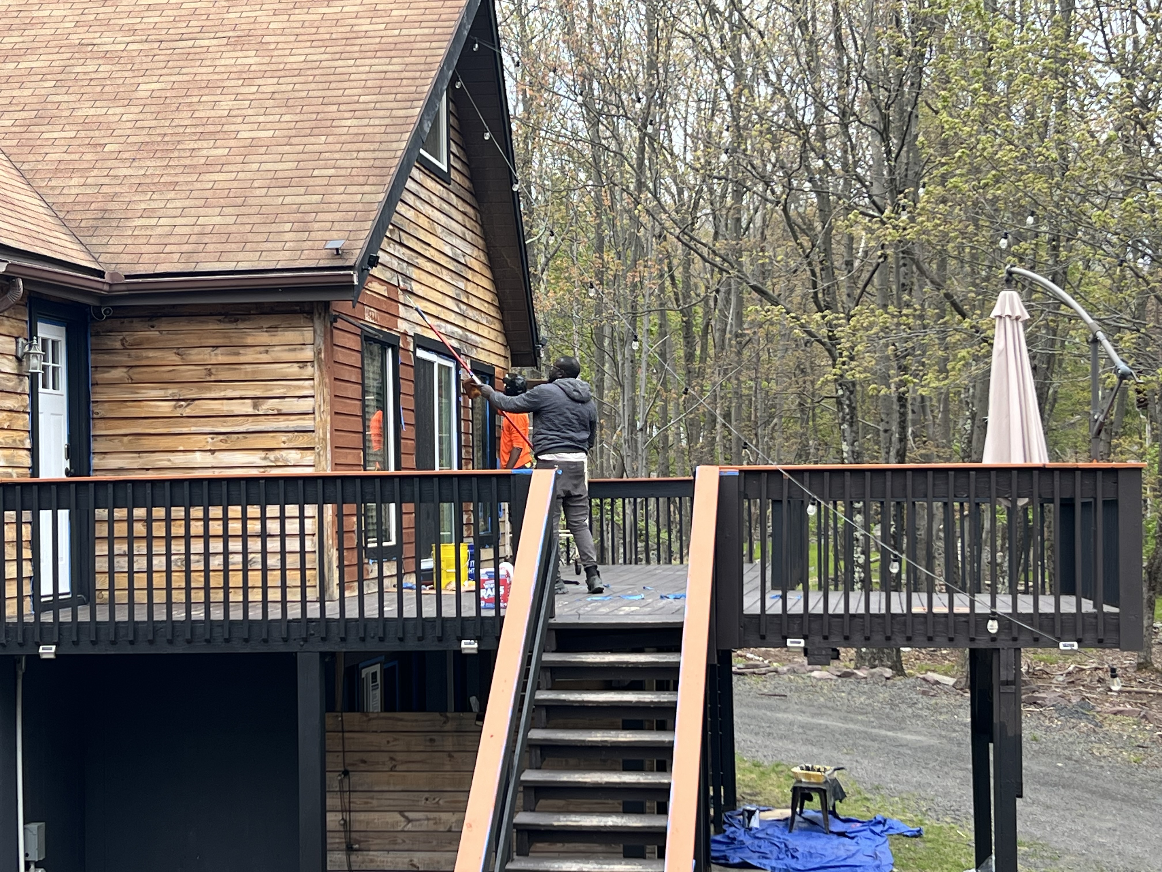 Poconos cabin in progress — wide exterior view of cabin deck, staircase, and facade paint work