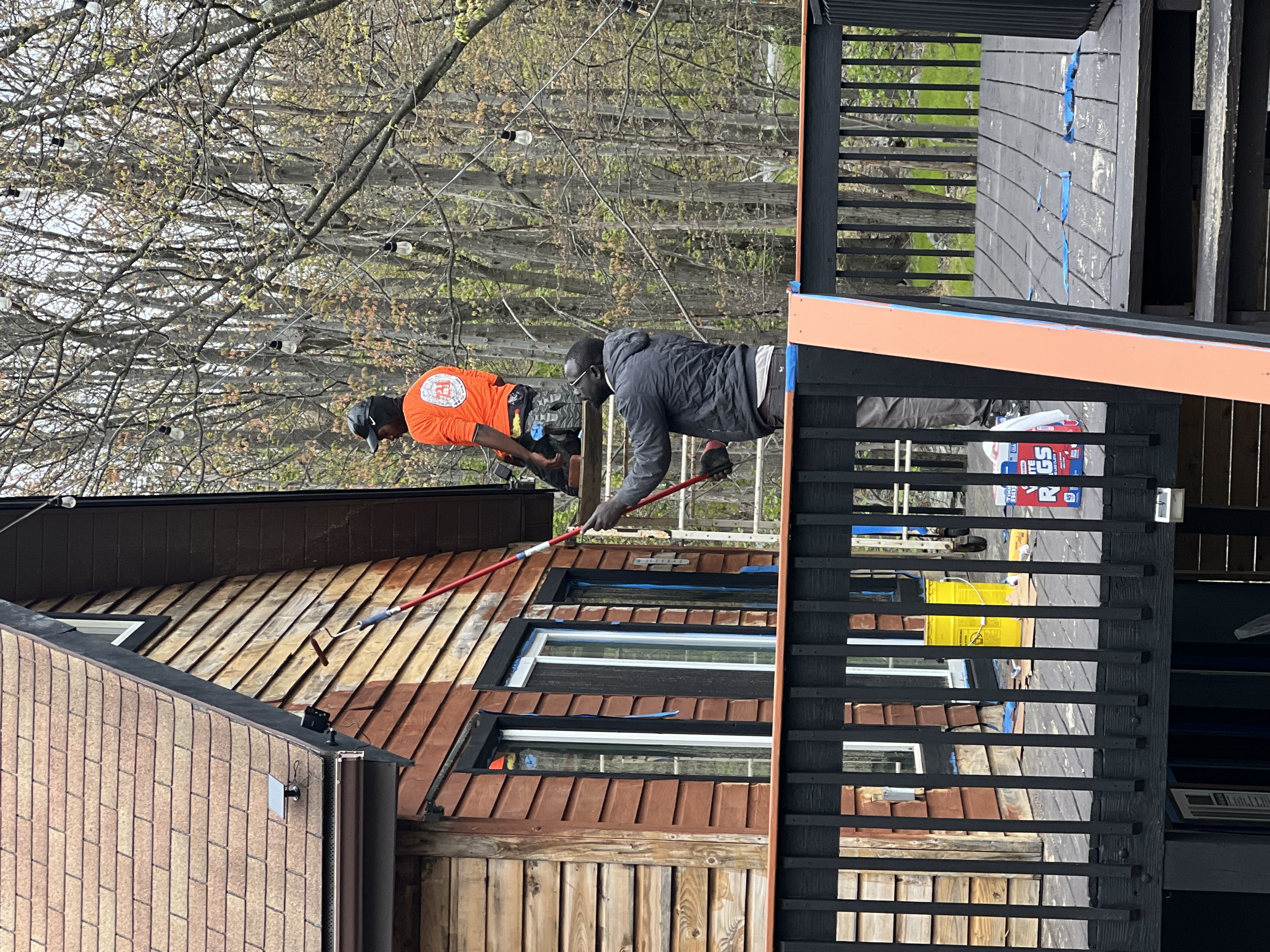 Poconos cabin in progress — painter using extension roller on upper cabin siding