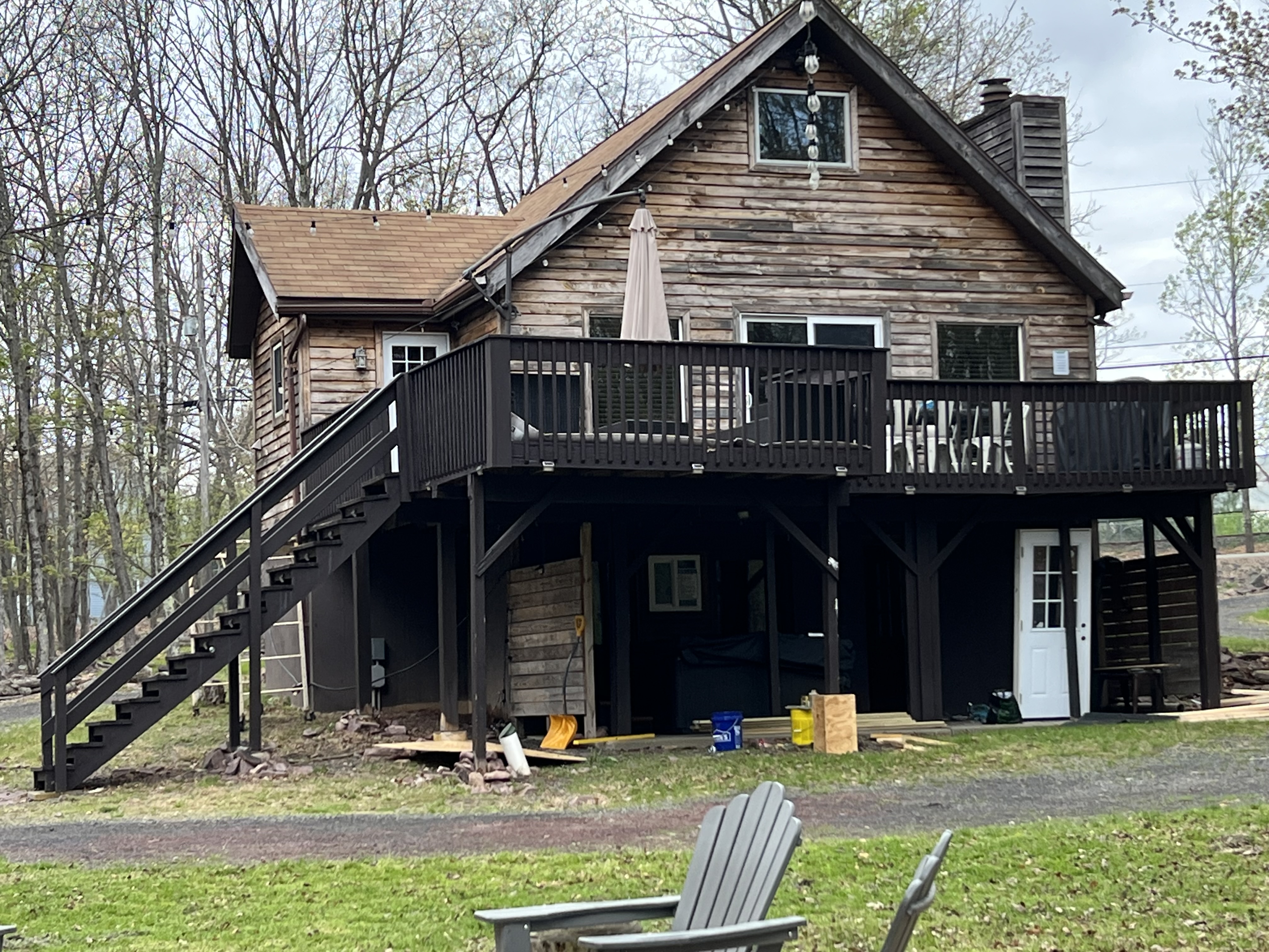 Poconos cabin before renovation — full exterior view showing faded, weathered wood siding and deck