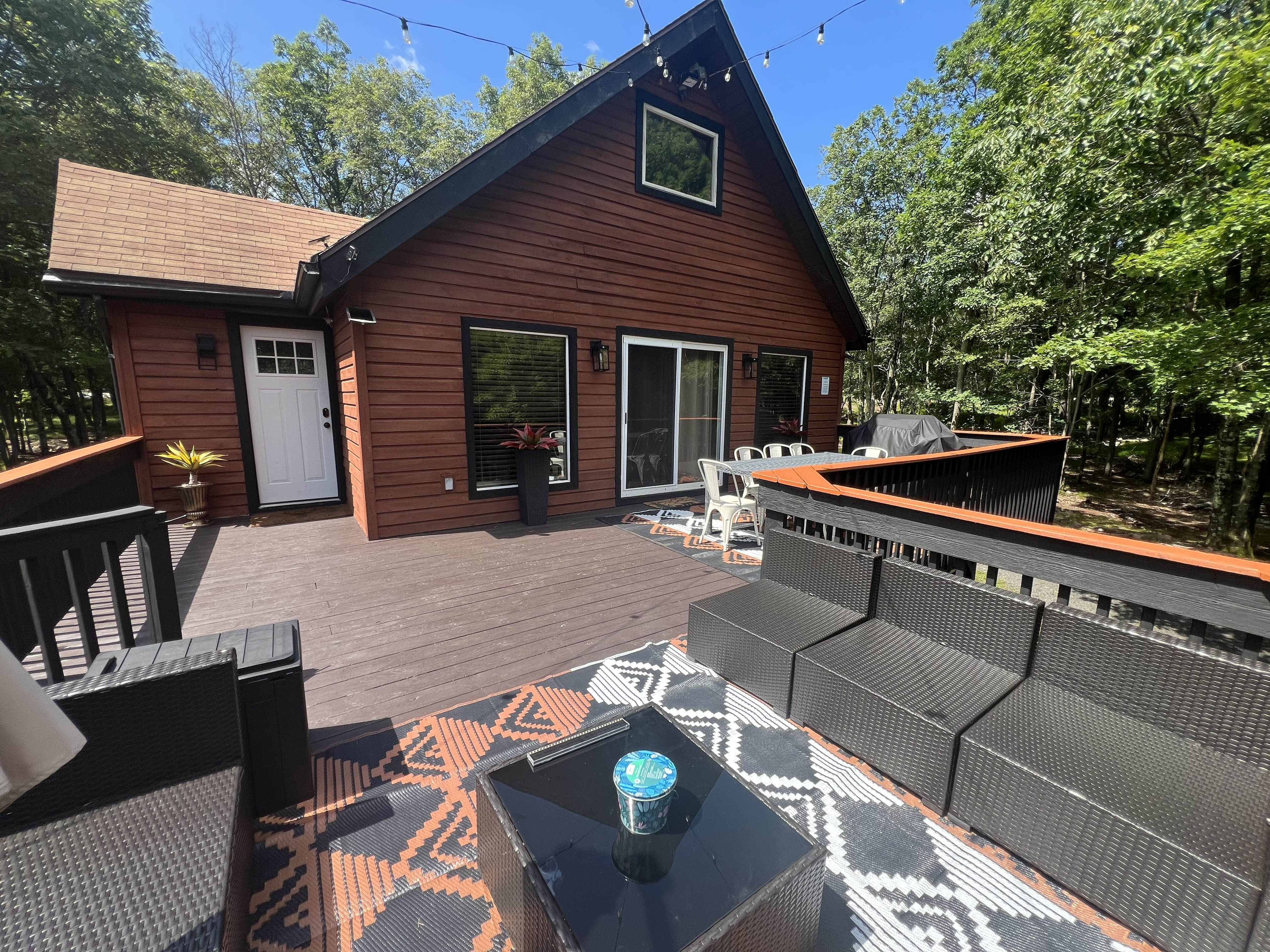 Finished Poconos cabin after renovation with freshly stained exterior siding, restored trim, and completed deck among the trees