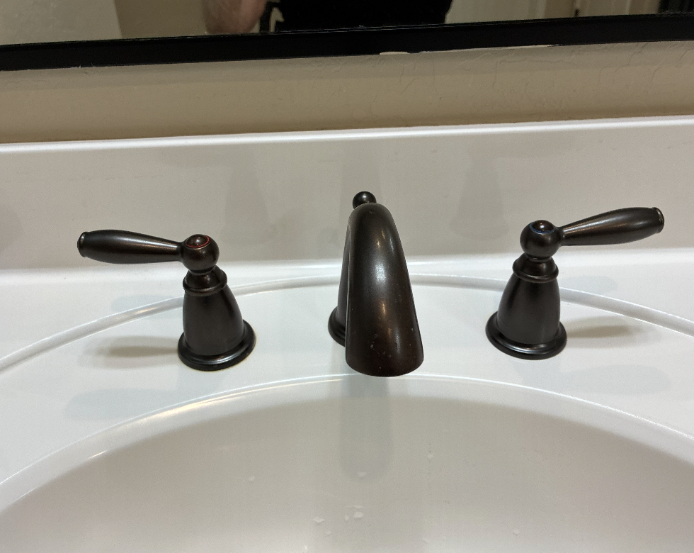 Oil rubbed bronze bathroom faucet and dual lever handles installed on white vanity sink by Aurora Plumbing in Peoria, AZ