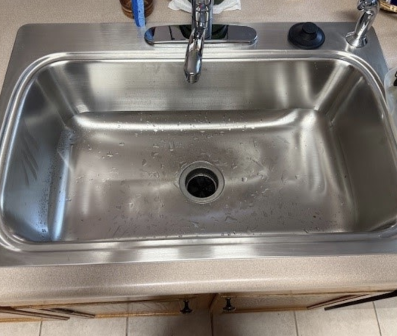 Stainless steel kitchen sink and chrome faucet installation by Aurora Plumbing
