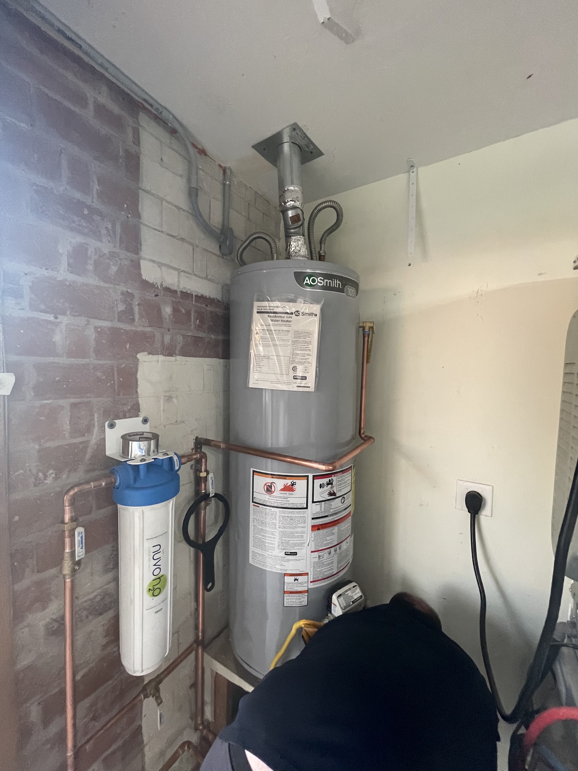 Aurora Plumbing technician installing a new tank water heater in a Peoria, AZ home garage