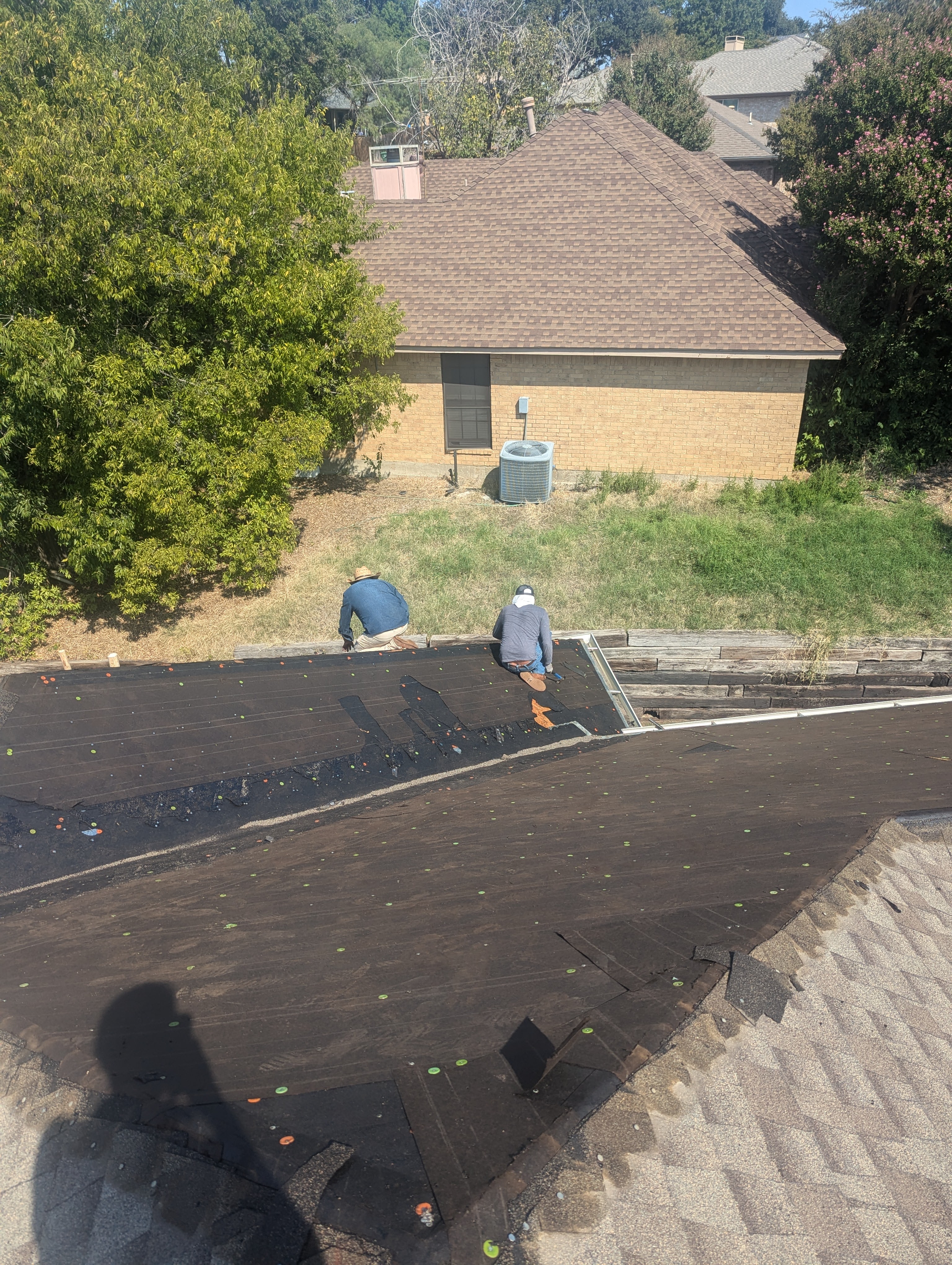 Roofing crew installing synthetic underlayment on a residential roof in West Plano TX