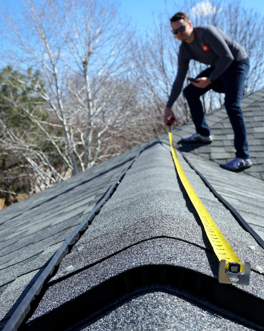 Photo of a roofing inspector pointing out hail hits or examining wind-damaged shingles on a roof slope