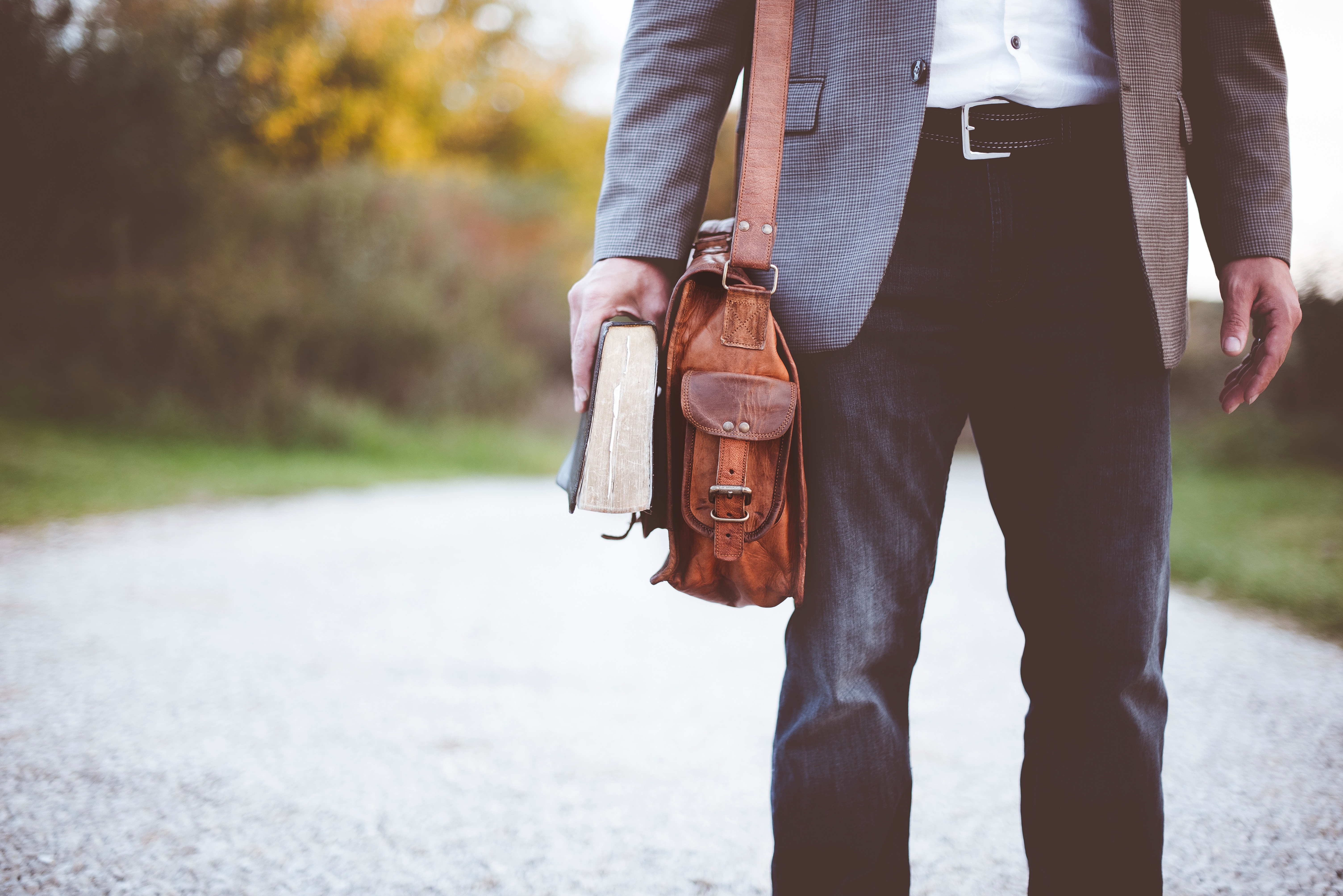 Student with Bible and leather bag walking on path
