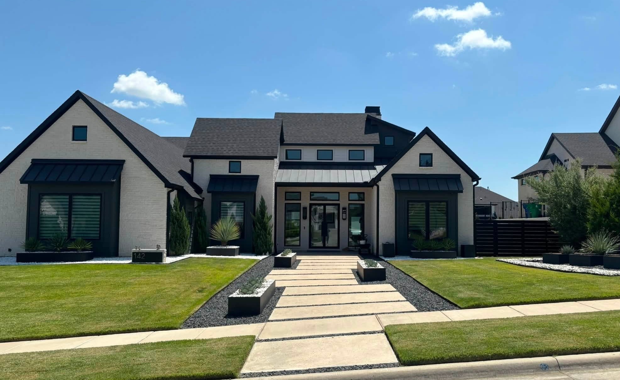 Luxury modern Texas home with architectural stepping-stone walkway, manicured lawn, and modern landscaping beds in Rockwall, TX