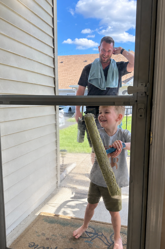 Tim Waldron and his son smiling while cleaning windows together