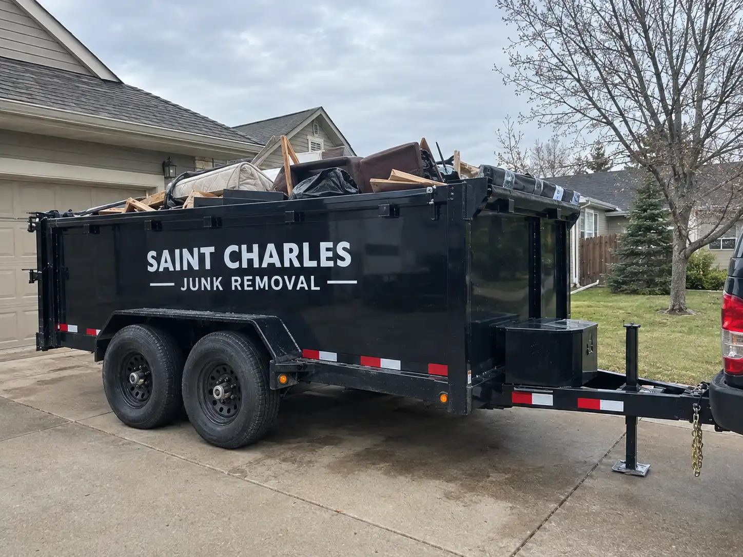 Saint Charles Junk Removal trailer filled with junk in a driveway