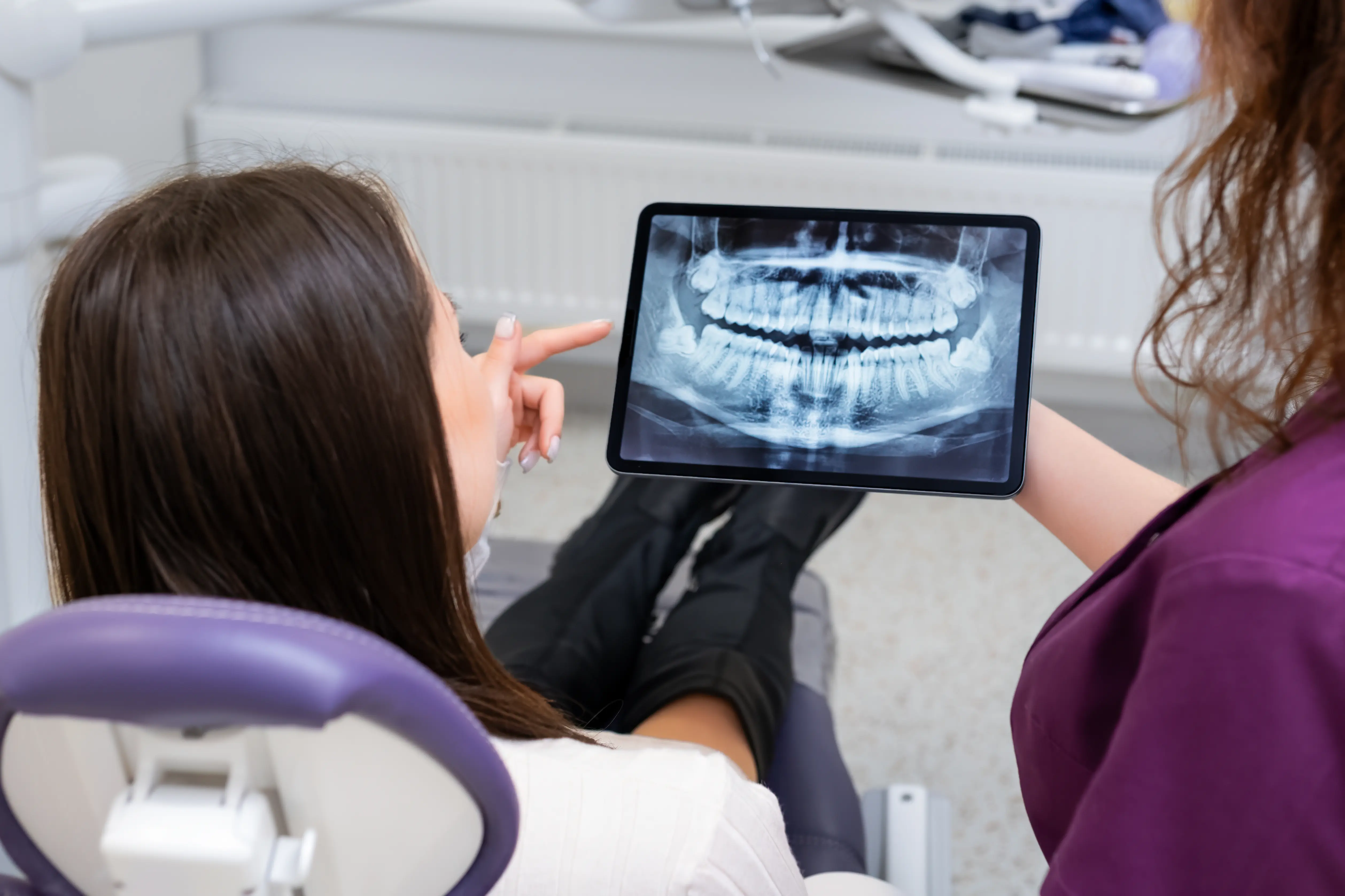 Patient et dentiste examinent une radiographie numérique sur tablette lors de la consultation