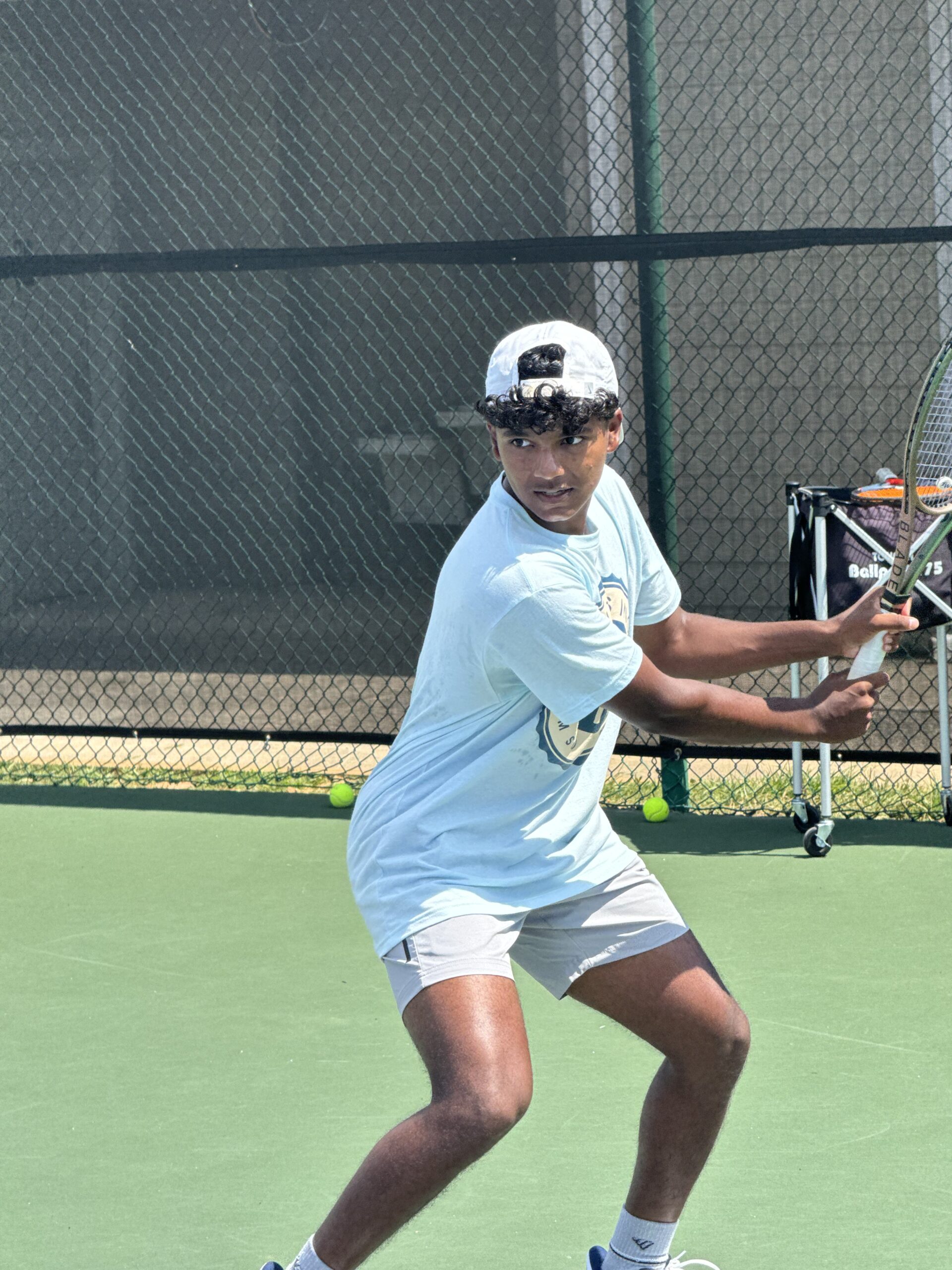 Junior male athlete in athletic stance preparing backhand stroke
