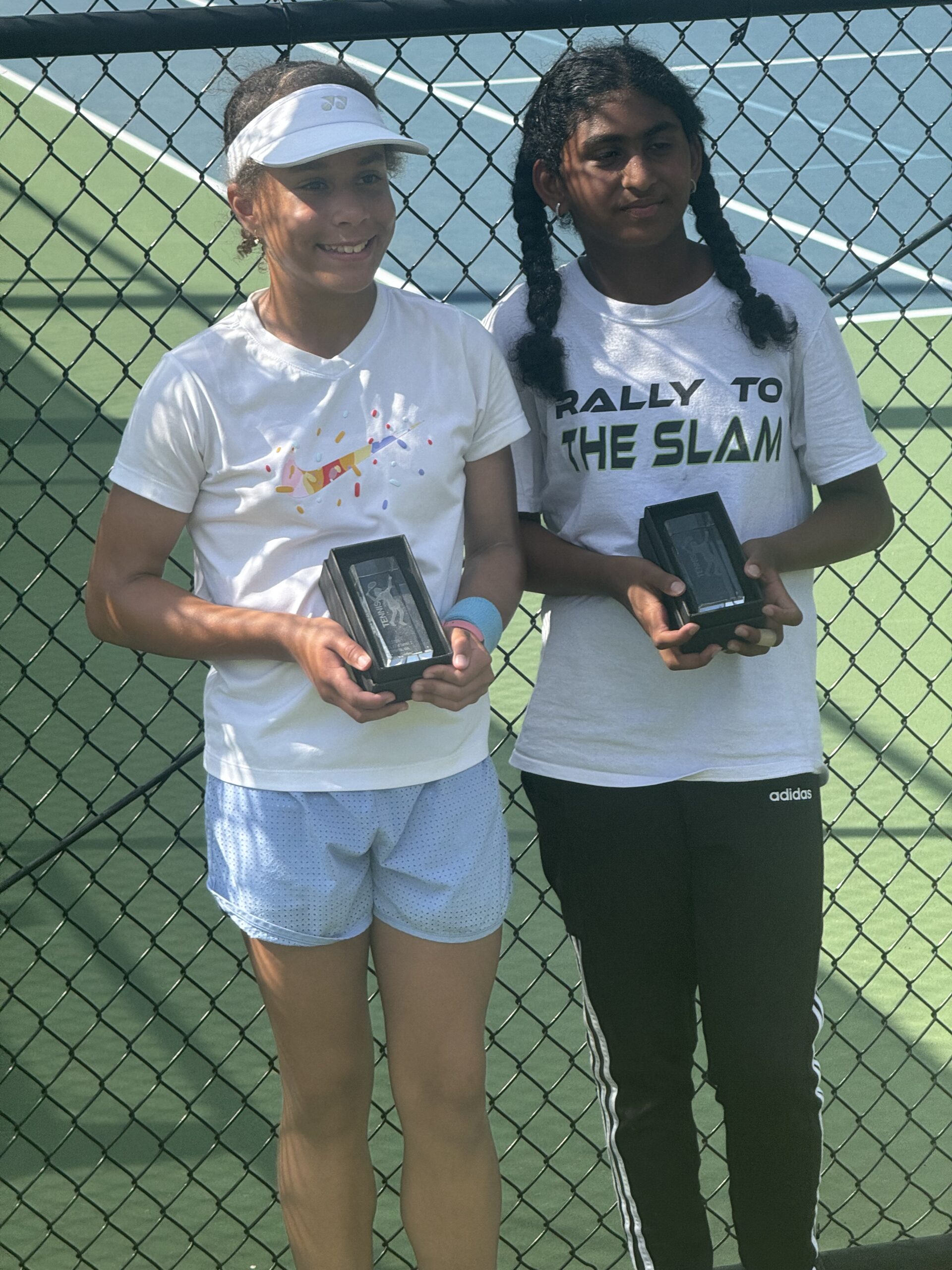 Junior girls smiling and holding tennis tournament trophy awards