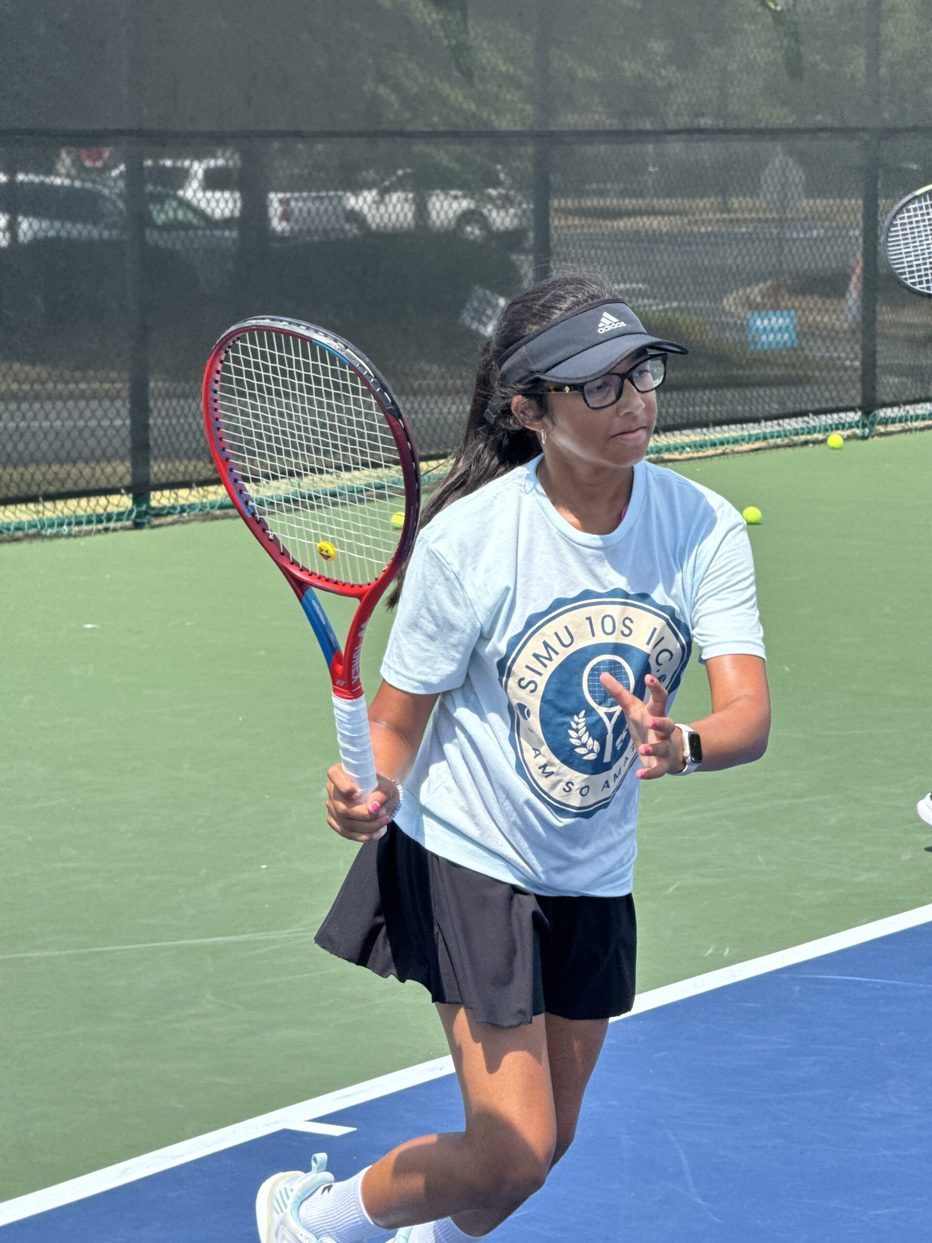 Young female athlete in Simu 10s shirt tracking ball with racket open