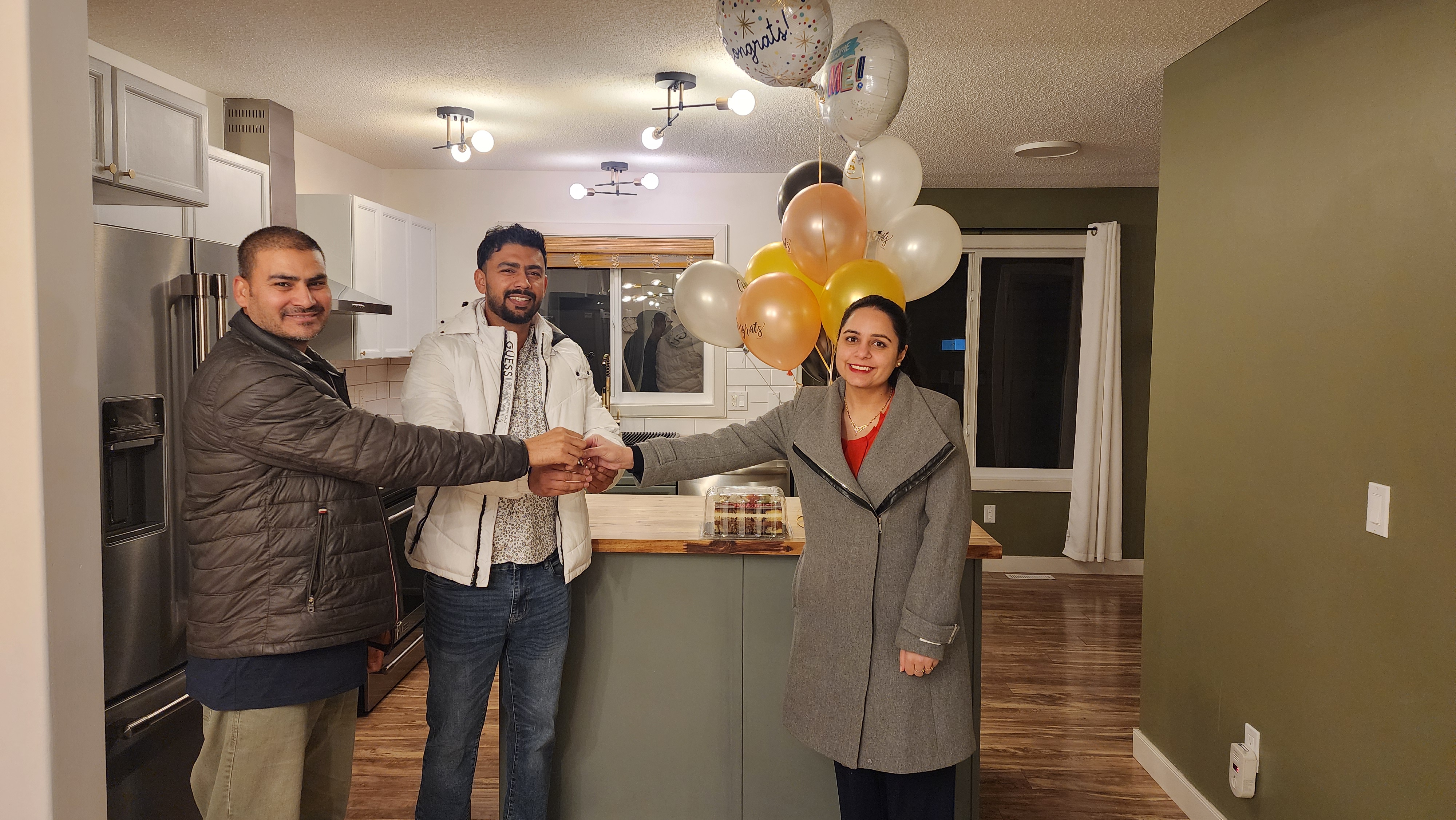 Athir Mehmood handing the keys to excited new homeowners in Fort McMurray