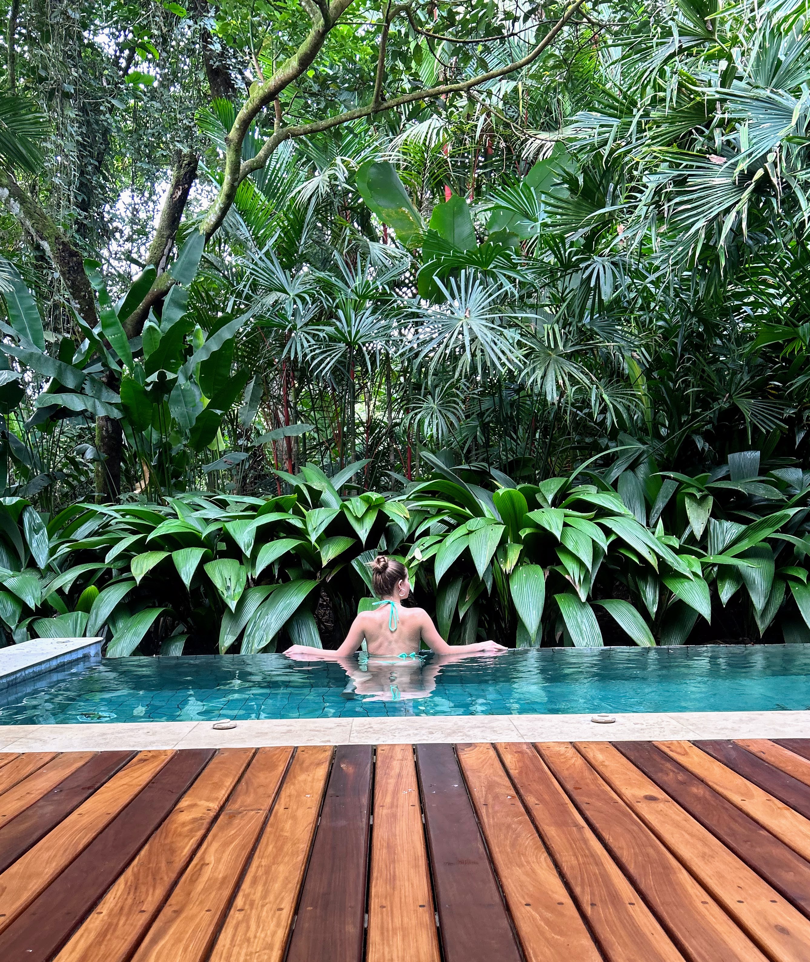 Guest relaxing in a secluded jungle infinity pool surrounded by tropical palms