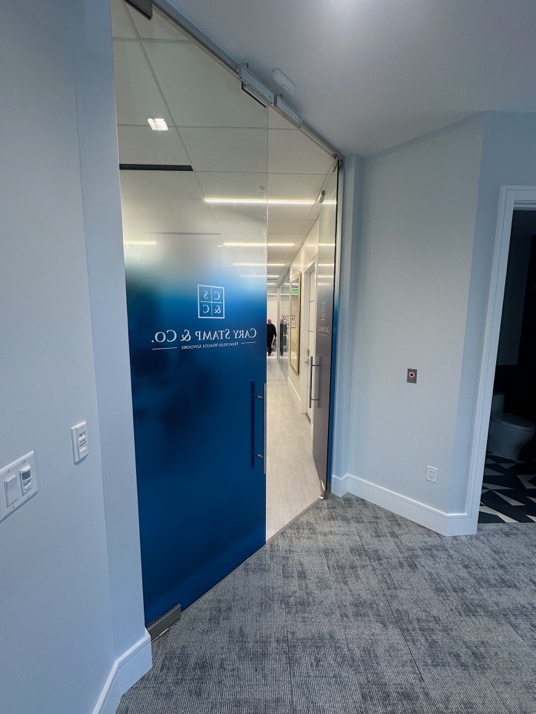 Commercial glass entrance door with frosted privacy film, modern door pull hardware, and access control push button in professional office