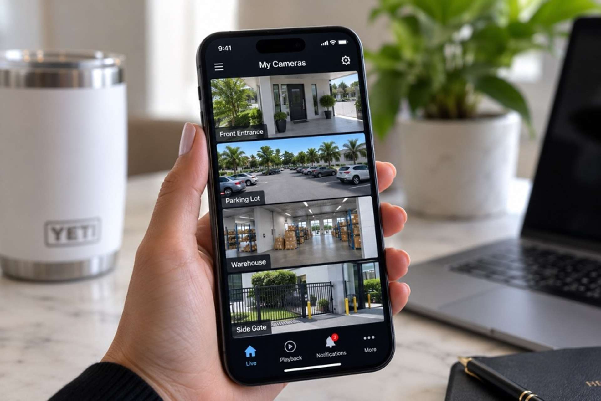 Smartphone displaying live multi-camera security feeds with front entrance, parking lot, warehouse, and side gate views