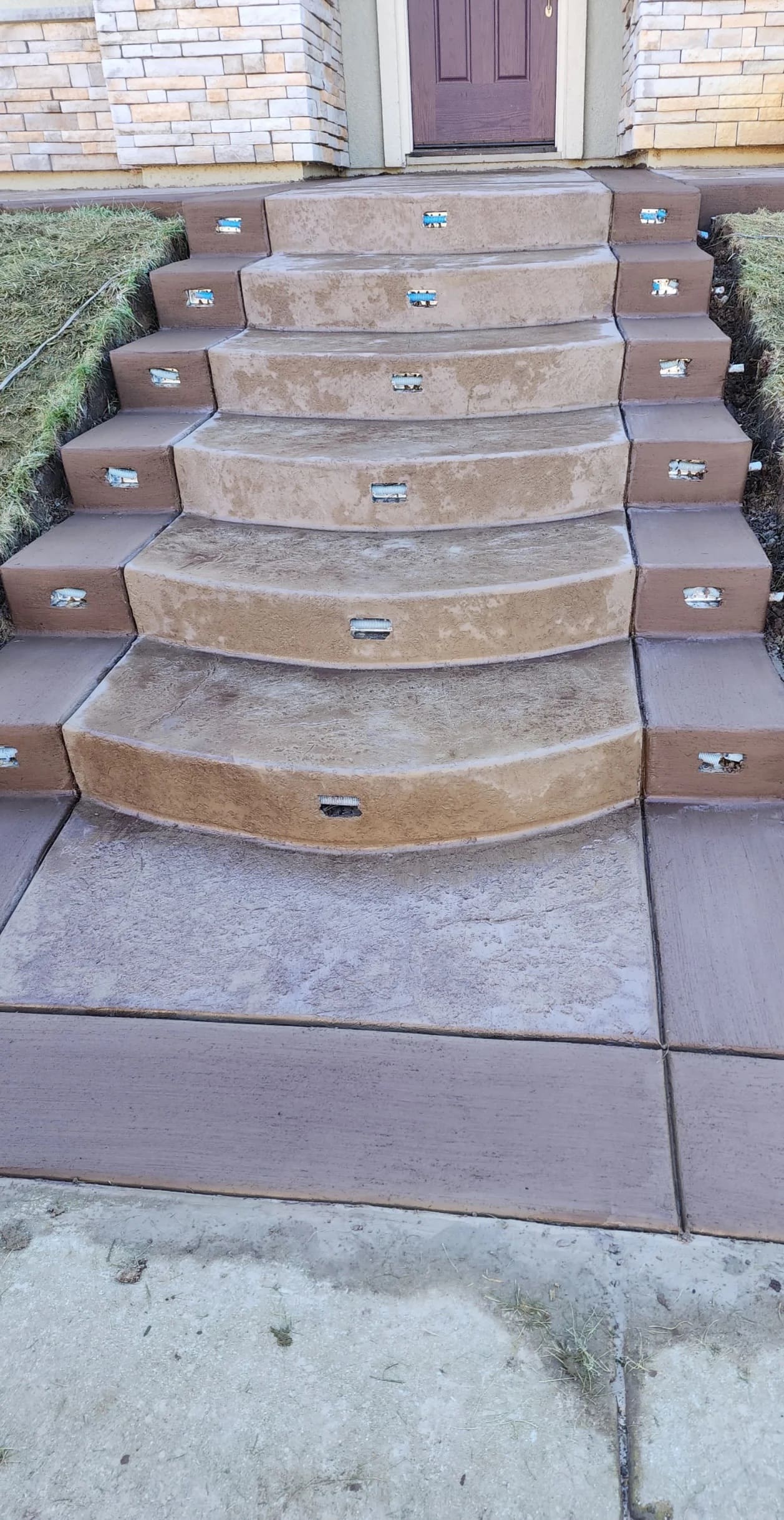 Curved decorative stamped concrete front entrance steps with integrated step lights and terraced borders