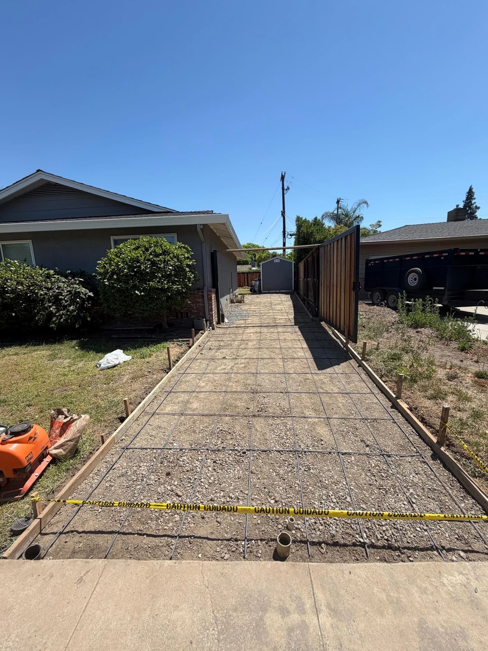 Concrete driveway preparation with rebar mesh, gravel base, and forms in side yard