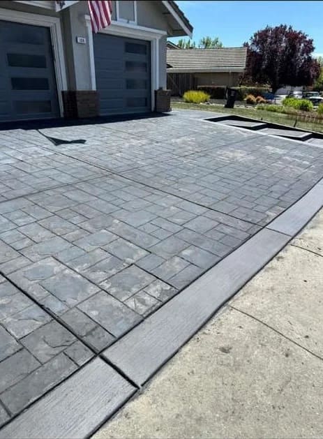 Ashlar slate stamped decorative concrete driveway with smooth troweled border in front of garage