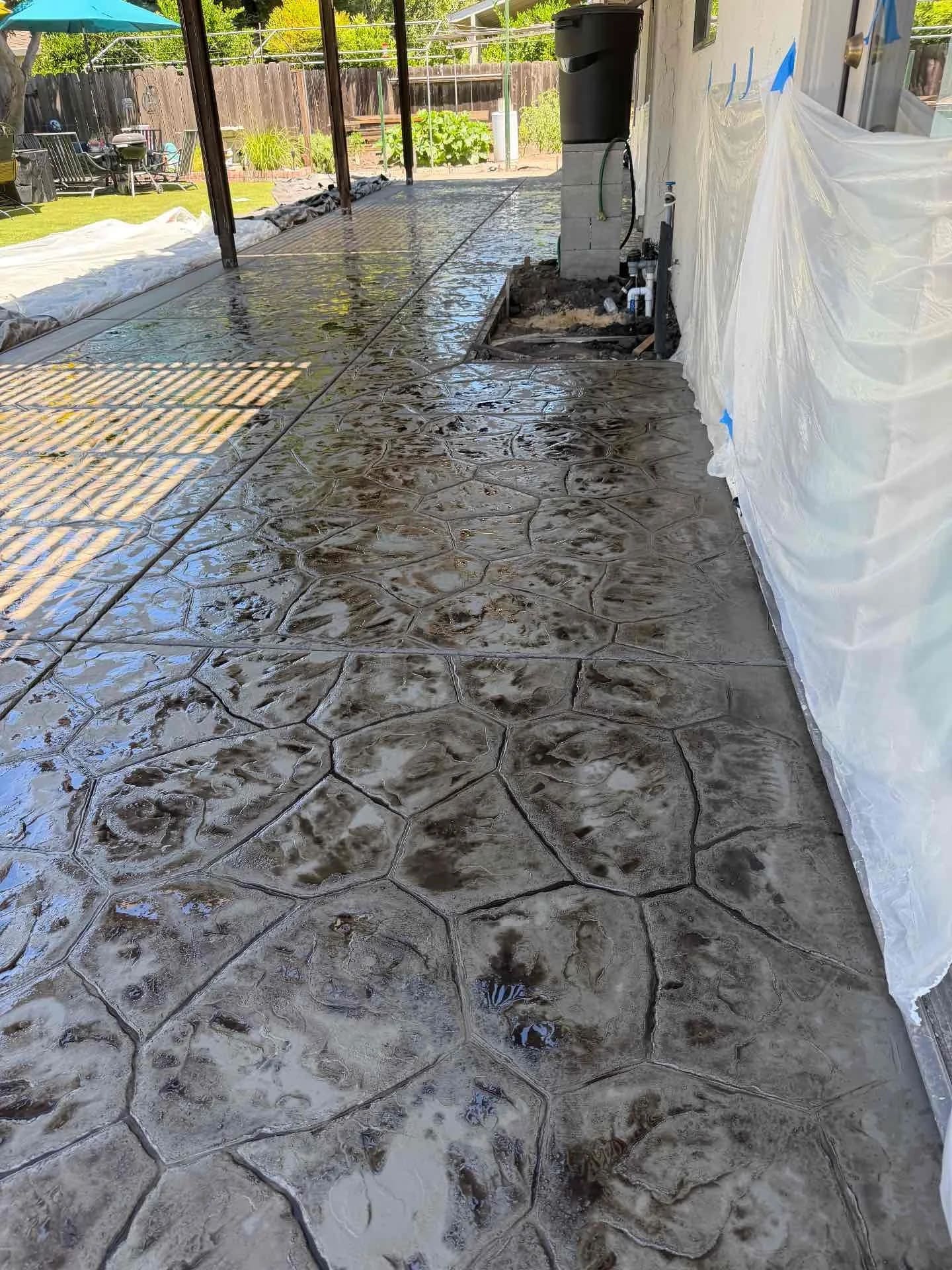 Gloss-sealed stamped flagstone concrete patio under outdoor covered patio structure